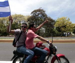 Two men from Managua take part in a caravan of solidarity towards Masaya demanding justice, democracy and the departure of President Daniel Ortega, in Masaya, Nicaragua on May 13, 2018. Nicaragua's army on Saturday called for an end to violence in the country and distanced itself from President Daniel Ortega, saying it was not repressing anyone for taking part in anti-government protests. The wave of unrest against Nicaraguan President Daniel Ortega which broke out in mid-April was triggered by an aborted attempt to reform the near-bankrupt social security system, but quickly expanded to include a wave of grievances against him, including claims of corruption and repression / AFP PHOTO / DIANA ULLOA