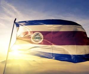 Costa Rica Rican flag on flagpole textile cloth fabric waving on the top sunrise mist fog
