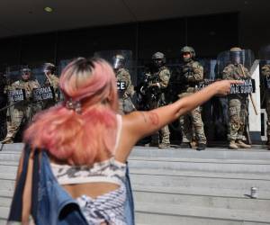 <i>Un mujer fue capada este martes, 10 de junio, al increpar a miembros de la Guardia Nacional de California que custodian la entrada del edificio federal, durante las protestas contra su presencia y las redadas a migrantes presuntamente indocumentados, en Los Ángeles (CA, EEUU). EFE/Allison Dinner</i>