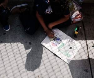 BROWNSVILLE, TX - JUNE 25: A Honduran child works in a coloring book while waiting with his family along the border bridge after being denied entry from Mexico into the U.S. on June 25, 2018 in Brownsville, Texas. Immigration has once again been put in the spotlight as Democrats and Republicans spar over the detention of children and families seeking asylum at the border. Before President Donald Trump signed an executive order last week that halts the practice of separating families who are seeking asylum, more than 2,300 immigrant children had been separated from their parents in the zero-tolerance policy for border crossers. Spencer Platt/Getty Images/AFP