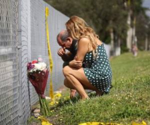 PARKLAND, FL - FEBRUARY 18: Maria Cristina and Vincent Collazo pray at the fence that runs around Marjory Stoneman Douglas High School on February 18, 2018 in Parkland, Florida. Police arrested 19 year old former student Nikolas Cruz for the mass shooting that killed 17 people on February 14. Joe Raedle/Getty Images