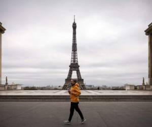 Un hombre corre frente a la Torre Eiffel el 21 de marzo de 2020 en París (Photo by Lionel BONAVENTURE / AFP)