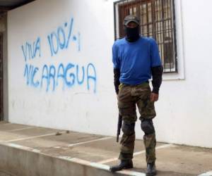 A paramilitary stands guard in a street of Monimbo neighborhood next to a grafitti reading 'Long live Nicaragua 100%' in Masaya, Nicaragua, on July 18, 2018, following clashes with anti-government demonstrators.The head of the Inter-American Commission on Human Rights has described as 'alarming' the ongoing violence in Nicaragua, where months of clashes between protesters and the forces of President Daniel Ortega have claimed almost 300 lives. / AFP PHOTO / MARVIN RECINOS