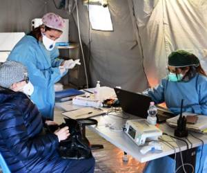 A ederly woman receives assistance in the a pre-triage medical tent in front of the Cremona hospital, in Cremona, northern Italy, on March 4, 2020. - Italy will recommend people stop kissing in public, avoid shaking hands and keep a safe distance from each other to limit the spread of the novel coronavirus. Other measures to be approved by the government, which has borne the brunt of the COVID-19 disease, includes a plan to play all football matches behind closed doors. (Photo by MIGUEL MEDINA / AFP)