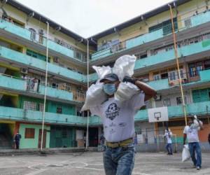 Voluntarios del Plan Panamá Solidaria entragan comida a familias de escasos recursos en El Chorrillo, Ciudad de Panamá. (Foto Luis ACOSTA / AFP)