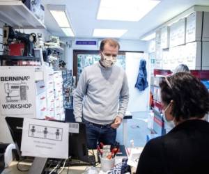 A customer (R) is served by the owner of a haberdashery in Brussels on May 4, 2020, as shops on a commercial street in the Belgian capital opened its doors on the first day of the partial lifting of restrictions in place to attempt to halt the spread of the new coronavirus (COVID-19). (Photo by Aris Oikonomou / AFP)