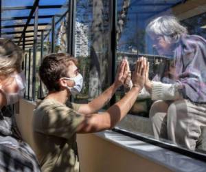 Brazilian Alexandre Schleier (C) speaks with his 81-year-old grandmother Olivia Schleier (R), next to his mother Eunice Schleier (L), through a window at the Premier Hospital, in Sao Paulo, Brazil, on May 28, 2020. - The hospital does not have any case of COVID-19 but does not permit visits to prevent contagions of the new coronavirus. (Photo by NELSON ALMEIDA / AFP)