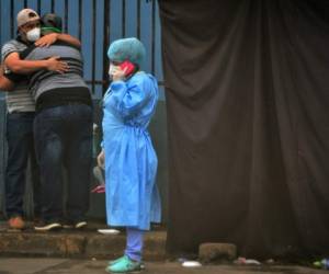 Relatives of an alleged COVID-19 victim embrace as a health worker speaks on the phone at a field hospital set up in the yard of the School Hospital in Tegucigalpa, on July 22, 2020. - At least 1,000 have died and 30,867 have been infected with COVID-19 in Honduras, amid corruption accusations against Honduran President Juan Orlando Hernandez in the purchase of seven mobile hospitals, biosecurity equipment and material. (Photo by ORLANDO SIERRA / AFP)