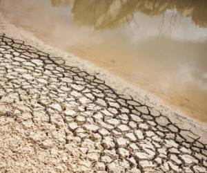 A dried out bank of a nearly water empty dam is pictured on a farm in Piket Bo-berg, Piketberg, north of Cape Town, on March 7, 2018 as a result of a three-year-long drought.Fruit farmers in the Piket Bo-Berg, who have been struggling with drought for the past three years, had to adapt their ways of farming to still be able to produce a profitable harvest. / AFP PHOTO / WIKUS DE WET