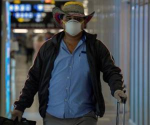 Un pasajero se cubre su máscara por el COVID-19, llega al aeropuerto de Tocumen el 13 de marzo de 2020. (Foto de Luis ACOSTA / AFP)