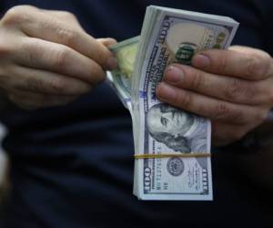 A man counts a pile of US Dollar bank notes in the Iraqi capital Baghdad on May 4, 2020, during the novel coronavirus pandemic crisis. - With its financial outlook darkening by the day, Iraq is considering slashing its massive public payroll -- an unpopular move likely to renew protests.OPEC's second-largest producer has been hit hard by the double-whammy of collapsed crude prices and the COVID-19 pandemic, which have hacked at its revenues from oil sales. (Photo by AHMAD AL-RUBAYE / AFP)