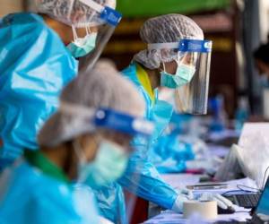 Medical workers take details from people, as hospitality and tourism workers are tested for the Covid-19 coronavirus on Khao San Road, in Bangkok on January 6, 2022. (Photo by Jack TAYLOR / AFP)