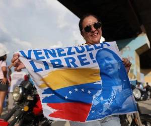 <i>Una mujer sostiene una bandera mientras espera la llegada de la líder opositora y premio nobel de la paz 2025, en Maracay (Venezuela). EFE/ Miguel Gutiérrez</i>