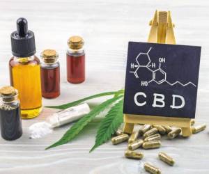 Full spectrum Cannabidiol CBD oils, capsules and crystals isolate with small blackboard with CBD word and chemical structure on wooden backdrop