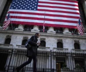 A man walks by the New York Stock Exchange (NYSE) on November 4, 2020 in New York. - Wall Street stocks were in rally mode Wednesday, shrugging off uncertainty over the still-unresolved presidential election and the likelihood of divided government in Washington.The Dow Jones Industrial Average was up 2.0 percent, or about 560 points, at 28,041.28 at around 1530 GMT, (Photo by Kena Betancur / AFP)