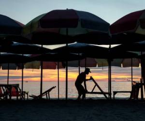 A man sets out deck chairs as the sun rises on the beach in Hua Hin on May 28, 2020, as Thailand continued to ease restrictions imposed to stop the spread of COVID-19 coronavirus. (Photo by Jack TAYLOR / AFP)
