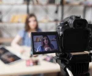 Young female beauty blogger on camera screen. Beautiful girl recording video at studio. Fashion, makeup, technology concept