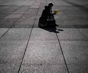 A woman reads a book on the esplanade at the business district of La Defense west of Paris on October 7, 2020 as the country faces a new wave of infections to the Covid-19 (the novel coronavirus). - La Defense, the largest European business district and the fourth largest in the world, had to reshape its activity following the Covid-19 pandemic: work from home, barrier measures and safety guidelines. According to Paris-La Defense association district, 60% of its workers have returned to the office. However, following the lockdown, the generalisation of home working, the partial closure of bars and restaurants and, now, the curfew, the daily life of some 500 companies and 180,000 employees is permanently affected. (Photo by Christophe ARCHAMBAULT / AFP)