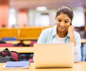 female indian university student using laptop in lecture room