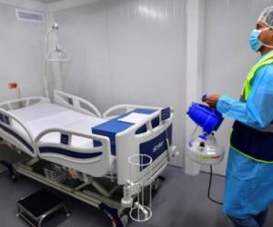 Un empleado pone desinfectante en un cuarto intergrado del Hospital 'Panama Solidario' para pacientes crónicos por COVID-19 en Ciudad de Panamá. (Foto de Luis ACOSTA / AFP)