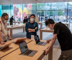 Customers (L and R) look at laptops at an Apple Store in Beijing on September 15, 2020. - Coronavirus-ravaged economies across the Asia Pacific are expected to contract this year for the first time in nearly six decades, throwing millions of people into poverty, the Asian Development Bank said. (Photo by NICOLAS ASFOURI / AFP)