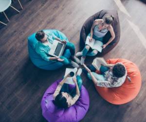 High top angle view of diversity stylish and modern hipster youngster sit in colorful armchairs on the wooden floor work together on the task sit classmates chair bag