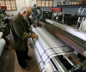 <i>Una persona trabaja junto a un telar en una fábrica textil. Imagen de archivo. EFE/Abed Al Hashlamoun</i>