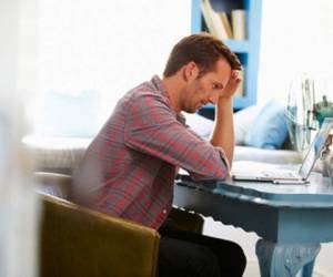 41393393 - stressed man at desk in home office with laptop