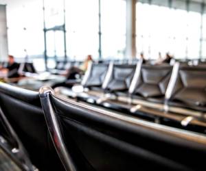 Airport interior with black trash can garbage bin in foreground and blurry bokeh background of waiting area at departure gate with nobody empty in USA