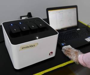 This photo taken on September 27, 2020 shows a technician in Beijing checking test results using the Flash 20 (L), a machine developed by Chinese biotech company Coyote as a fast test for the COVID-19 coronavirus. (Photo by GREG BAKER / AFP)