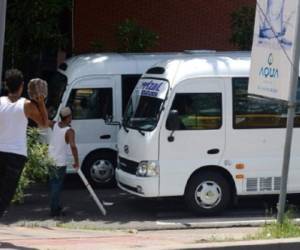 Trabajadores del transporte urbano obligan a un colega a sumarse a la marcha contra la extorsión de las pandillas y la violencia, ayer en Tegucigalpa. (Foto: AFP).