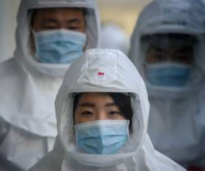 En esta foto del 12 de marzo de 2020, trabajadores usan equipo protector contra el COVID-19 en la Universidad Keimyung, en Daegu, Corea del Sur. (Foto de Ed JONES / AFP)
