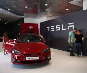 (FILES) In this file photo taken on March 24, 2020 a Tesla employee cleans a car outside a Tesla showroom in Burbank, California. - Tesla on October 21, said profits in the past quarter more than doubled as the electric car giant forecast deliveries hitting 500,000 this year.Net profit in the quarter rose to $331 million, up from $143 million a year earlier, as revenue rose nearly 40 percent to $8.7 billion. (Photo by Robyn Beck / AFP)