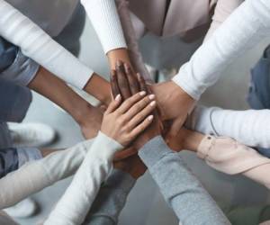 Close up of international business team showing unity with putting their hands together on top of each other. Concept of teamwork, top view