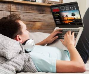 Man watching streaming series in a laptop computer, lying in the bed.