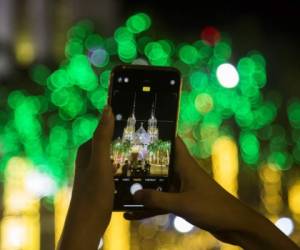 Una niña toma una foto con su teléfono móvil de la Catedral de Santa María iluminada en Navidad en Yangon el 25 de diciembre de 2020 (Foto de Sai Aung MAIN / AFP)