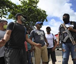 Honduran migrants, who were heading in a caravan to the US, speak with a police officer at a checkpoint after voluntarily agreeing to return to theirr country, in Morales, Guatemala on October 3, 2020. - Over 2.000 Hondurans requested local authorities to return to their country, according to police data sent to journalists. Guatemalan President Alejandro Giammattei on Thursday had ordered the detention of thousands of Hondurans who entered the country as part of a US-bound migrant caravan. (Photo by Johan ORDONEZ / AFP)