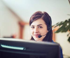 Beautiful business woman working at her desk with headset and laptop