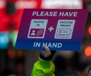 NEW YORK, NY - DECEMBER 31: A person holds a sighn at a check point as revelers gather ahead of New Year's Eve celebrations in Times Square thwarting off fears of the Omicron CoronaVirus variant on December 31, 2021 in New York City. Despite record numbers of COVID-19 cases across the city and nationwide, New York City is moving forward with New Years Eve celebrations. On average, about one million revelers are drawn to the Times Square to watch performances and celebrate. David Dee Delgado/Getty Images/AFP (Photo by David Dee Delgado / GETTY IMAGES NORTH AMERICA / Getty Images via AFP)