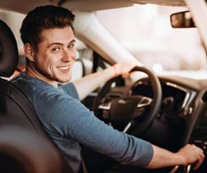 Happy young driver behind the wheel of a car. Buying a car and driving concept