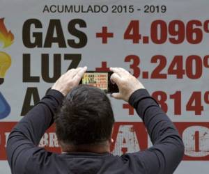 (FILES) In this file photo taken on August 15, 2019 a cashier counts Argentine pesos bills at a supermarket in Buenos Aires. - With unpaid credit cards, debts with the psicologyst and children's schools, middle class in Argentina is in crisis and in the border of default, as public accounts are. (Photo by JUAN MABROMATA / AFP)