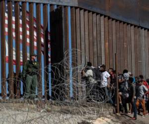 (FILES) In this file photo taken on November 25, 2018 Central American migrants look through a border fence as a US Border PatRol agents stands guard near the El Chaparral border crossing in Tijuana, Baja California State, Mexico. - Agence France-Press (AFP) photographer Guillermo Arias on September 7, 2019 won the top prize at photojournalism's biggest annual festival for his coverage of migrants from Central America. Arias, who is from Mexico, scooped the Visa d'Or for News, the most prestigious award handed out at the 'Visa Pour L'Image' festival in Perpignan, southwestern France. (Photo by GUILLERMO ARIAS / AFP)