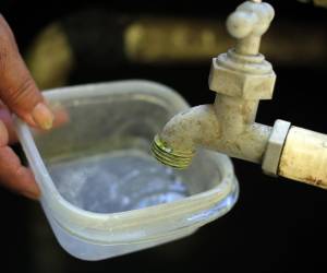 Fotografía de archivo de una persona intenta llenar un recipiente con agua. EFE/ Gustavo Amador