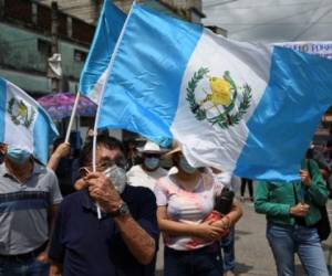 Demonstrators hold Guatemalan flags during a protest to demand the resignation of Guatemalan President Alejandro Giammattei and Guatemala's Attorney General Maria Consuelo Porras after Guatemala's Special Prosecutor against Impunity Juan Francisco Sandoval was dismissed, outside the Public Ministry's headquarters in Guatemala City on July 24, 2021. (Photo by Johan ORDONEZ / AFP)