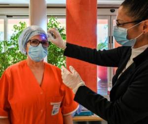 A nurse (L) is being monitored for body temperature on March 18, 2020 at the new COVID 3 level intensive care unit for coronavirus COVID-19 cases at the Casal Palocco hospital near Rome, that is to open later March 18. (Photo by ANDREAS SOLARO / AFP)