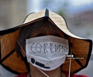 A woman wears a face mask reading Corrupt during a protest in demand of the resignation of Guatemalan President Alejandro Giammattei, at Constitution Square in Guatemala City on August 22, 2020, amid the COVID-19 coronavirus pandemic. (Photo by Johan ORDONEZ / AFP)