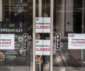 NEW YORK, NY - MARCH, 17: A woman hangs a sign in a restaurant due to closures in the wake of the Coronavirus, COVID19, outbreak on March 17, 2020 in New York City. Schools, businesses and most places where people congregate across the country have been shut down as health officials try to slow the spread of COVID-19. Victor J. Blue/Getty Images/AFP