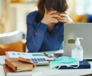 Closeup on medical mask and hand disinfectant and stressed woman in background in temporary home office during the coronavirus epidemic in the house in sunny day.