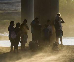 Una familia migrante de Venezuela se encuentra en medio de una tormenta de polvo mientras son detenidos por tropas de la Patrulla Fronteriza y la Guardia Nacional de EE. UU. en Eagle Pass, Texas, cerca de la frontera con México el 30 de junio de 2022. CHANDAN KHANNA / AFP