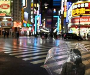 People wait to cross a street on Saturday night in almost empty Tokyo's Shinjuku area on April 11, 2020 (Photo by CHARLY TRIBALLEAU / AFP)